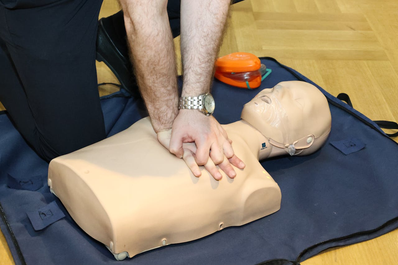 Hands performing CPR on a training dummy using realistic techniques indoors.